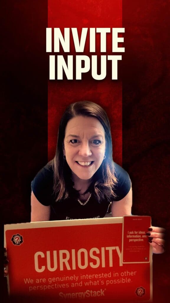 Karin Hurt holding a bit curiosity sign and the synergystack card that says invite input